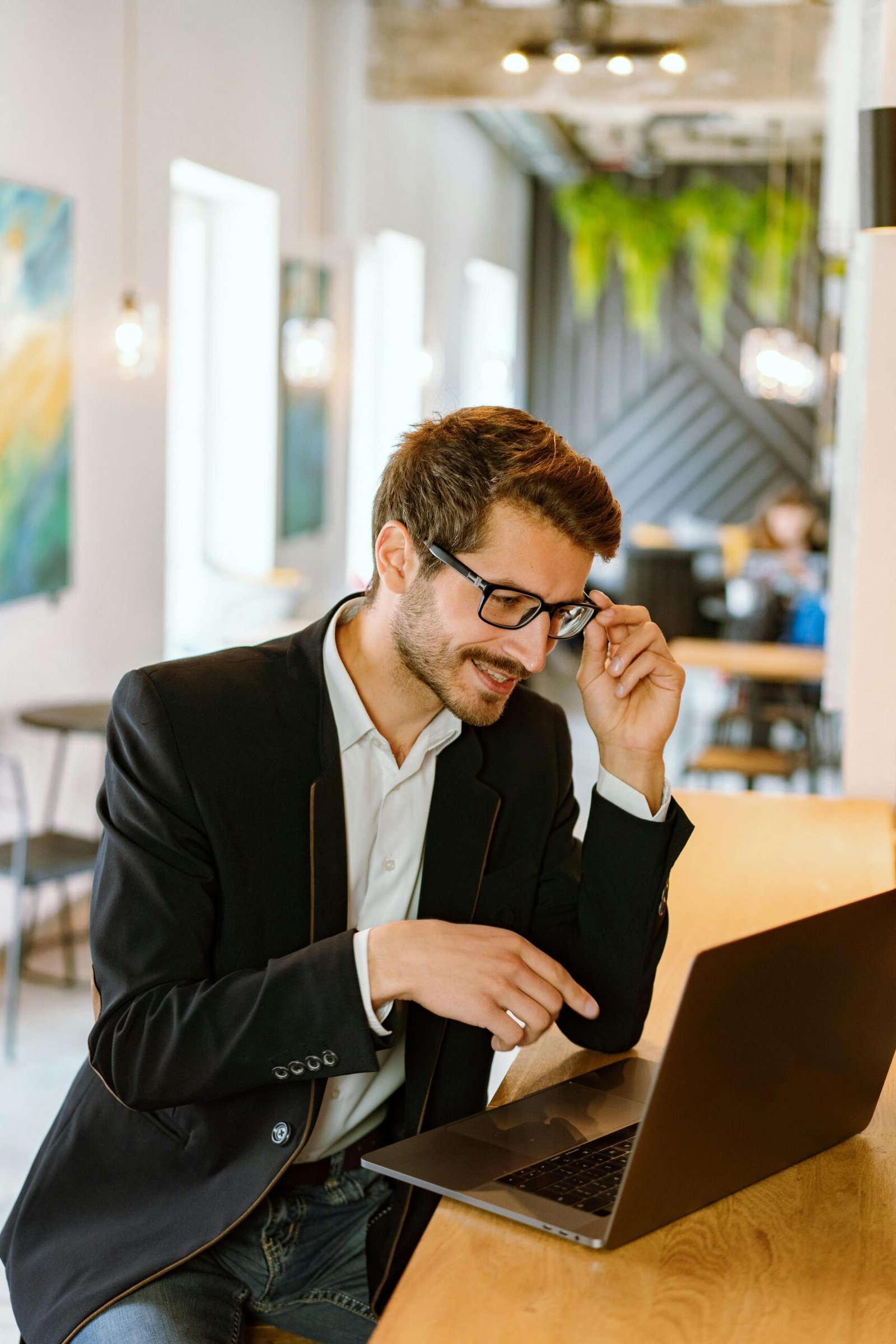 Businessman with glasses working on a laptop in a stylish modern office setting.